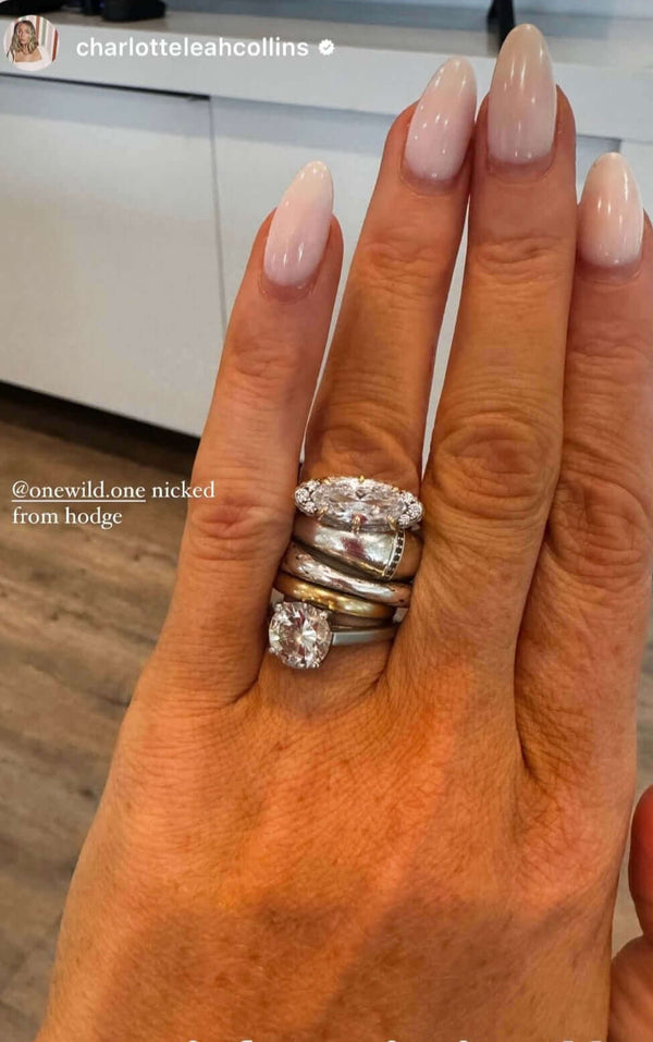 The Rest Of The World Can Wait East-West Silver Ring on a hand with long nails and a warm background.