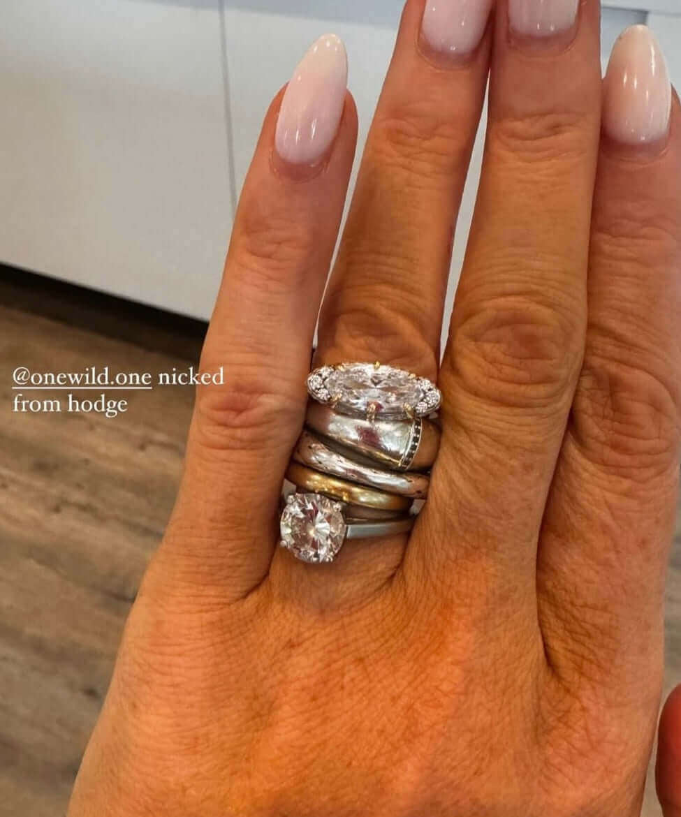 The Rest Of The World Can Wait East-West Silver Ring on a hand with long nails and a warm background.