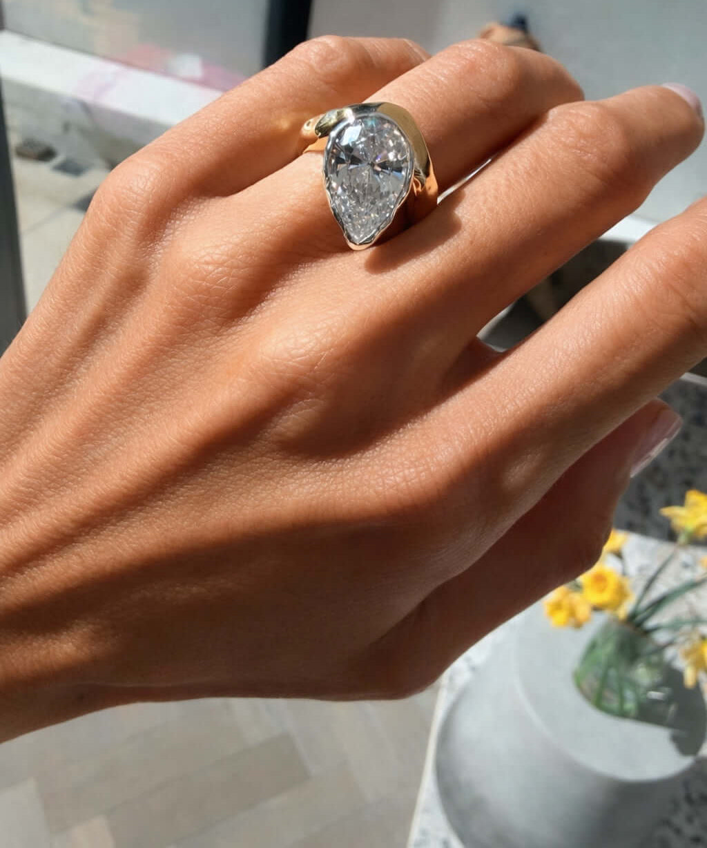 Hand wearing the Perfectly Imperfect Ring featuring a pear-cut stone and molten gold band.