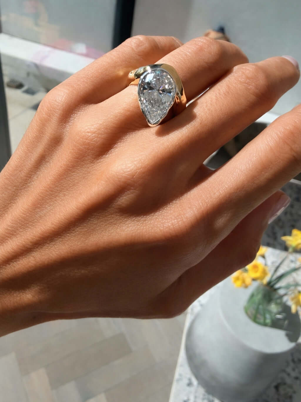 Hand wearing the Perfectly Imperfect Ring featuring a pear-cut stone and molten gold band.