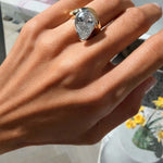 Hand wearing the Perfectly Imperfect Ring featuring a pear-cut stone and molten gold band.