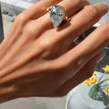 Hand wearing the Perfectly Imperfect Ring featuring a pear-cut stone and molten gold band.