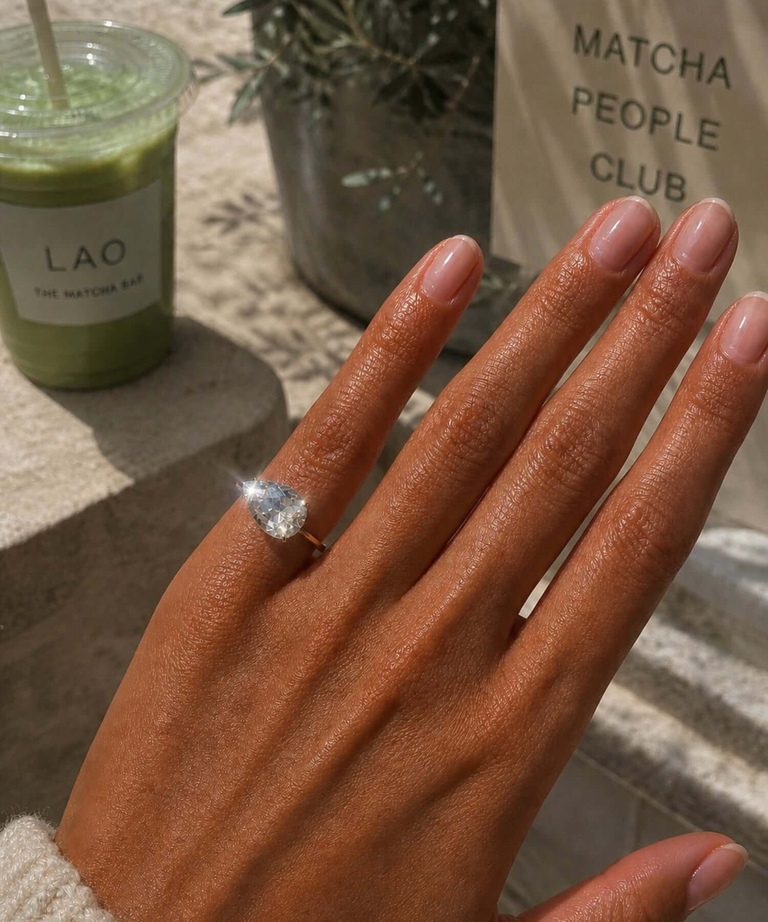 Showing the Kind Is Cool Pinky Ring worn on a hand, with a matcha drink in the background.