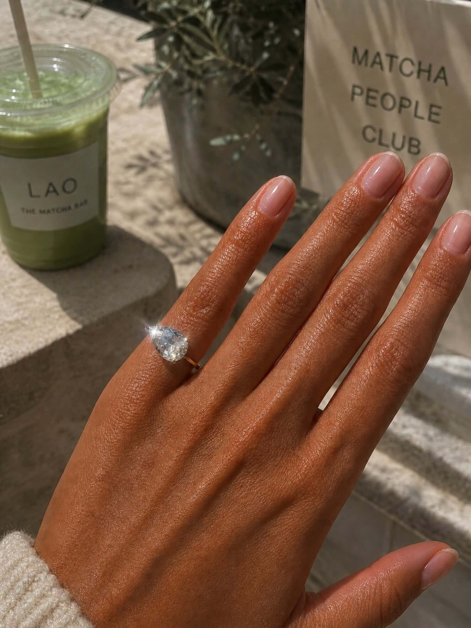Showing the Kind Is Cool Pinky Ring worn on a hand, with a matcha drink in the background.