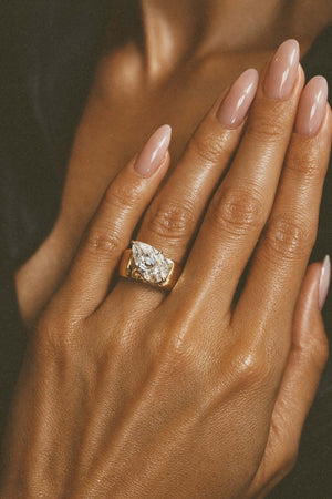 A Wonderful Thing Tilted Pear Cigar Band Ring worn on a hand with elegant nails, showcasing its cubic zirconia and gold finish.