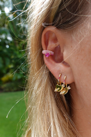Love Is Love Rainbow Huggie Earrings With Detachable Heart Charm worn in an ear, showcasing vibrant colors and stylish design.