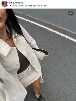 Close-up of a woman in a light coat and mini skirt, showcasing her casual street style.