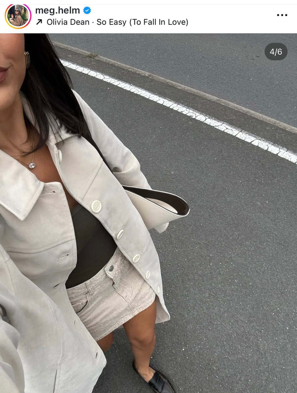 Close-up of a woman in a light coat and mini skirt, showcasing her casual street style.