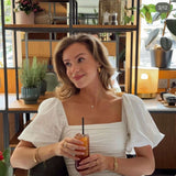 True Love Story Oval Solitaire Necklace worn by a woman enjoying a drink in a stylish cafe setting.