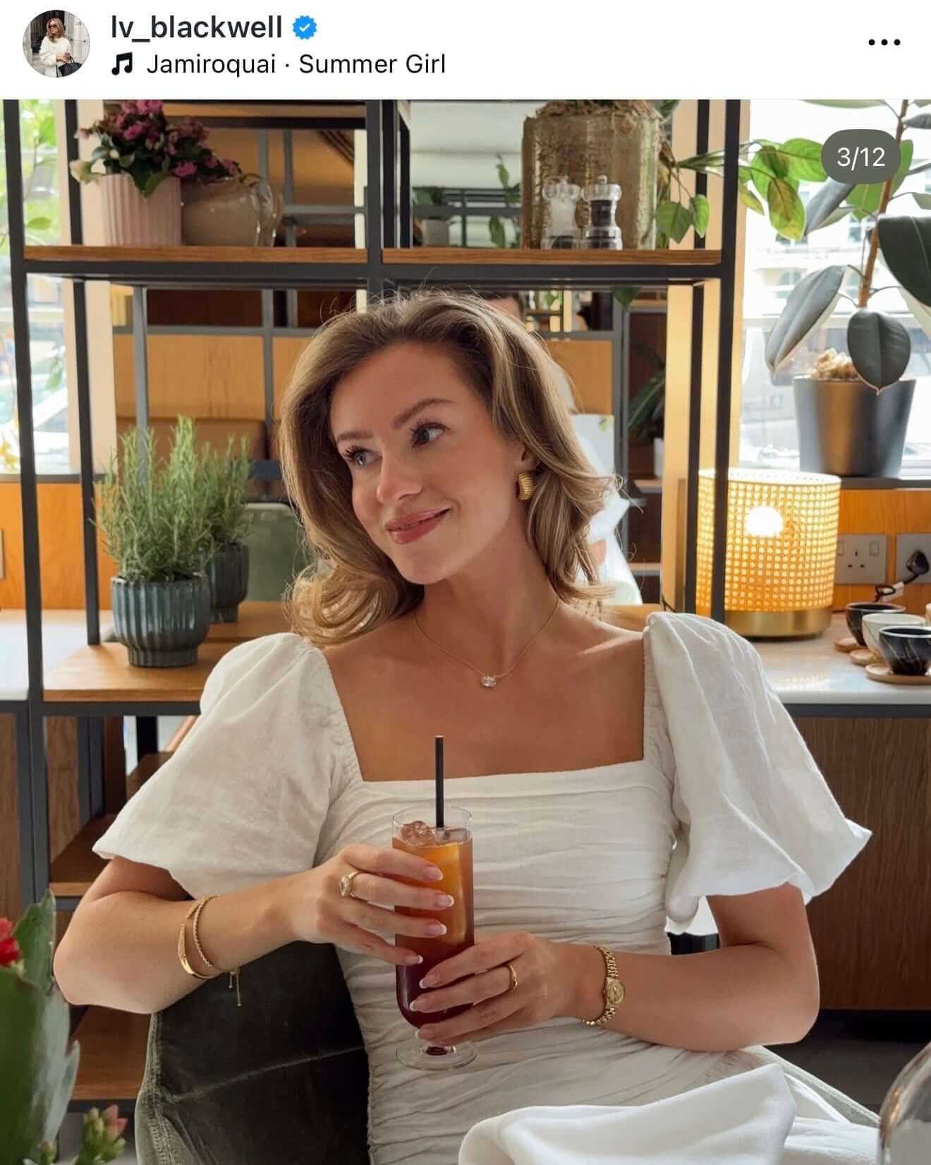 True Love Story Oval Solitaire Necklace worn by a woman enjoying a drink in a stylish cafe setting.