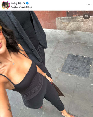 Selfie of a woman in a black outfit taking a picture on a city street.