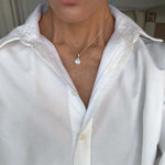 Model wearing the Time To Shine Pendant Necklace with a white shirt, showcasing its elegant design and pear drop pendant.