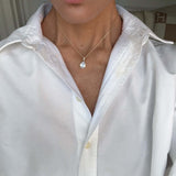 Model wearing the Time To Shine Pendant Necklace with a white shirt, showcasing its elegant design and pear drop pendant.