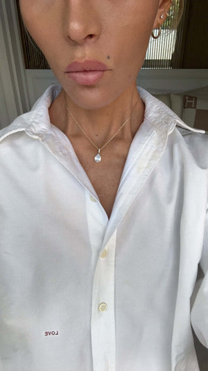 Model wearing the Time To Shine Pendant Necklace with a white shirt, showcasing its elegant design and pear drop pendant.