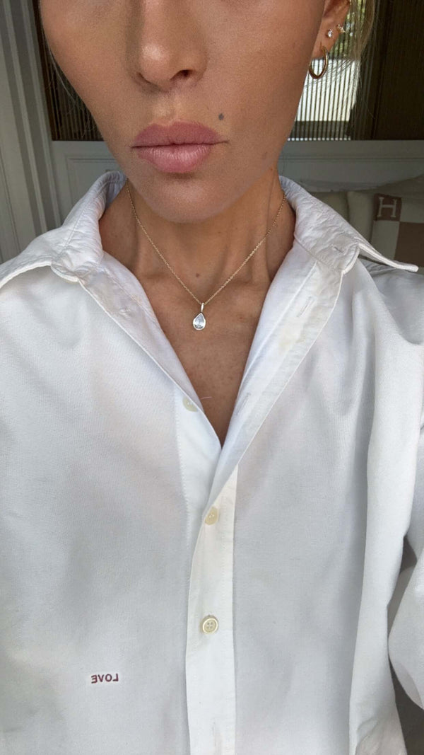 Model wearing the Time To Shine Pendant Necklace with a white shirt, showcasing its elegant design and pear drop pendant.