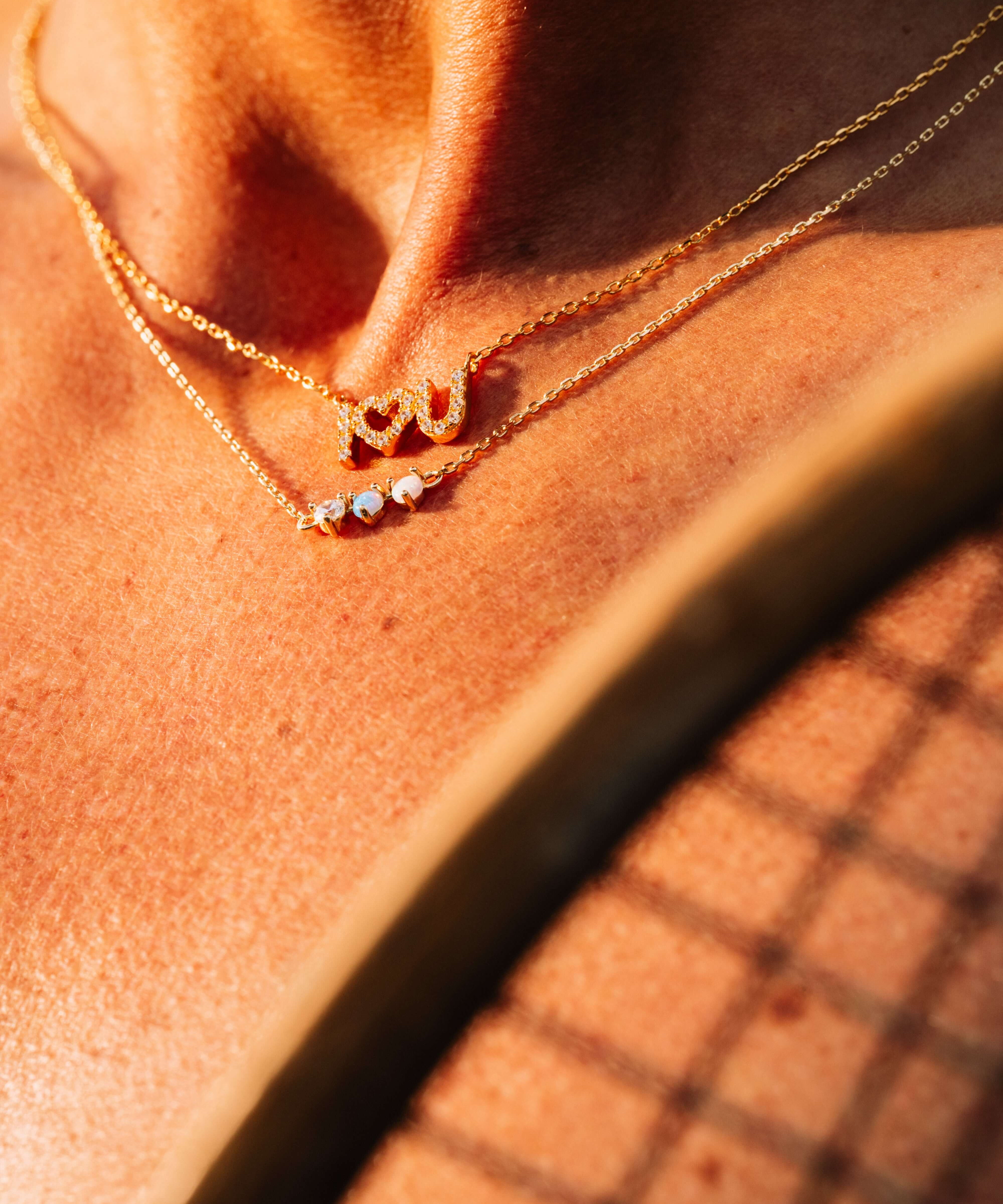 Starburst Opal Pendant Necklace elegantly layered with delicate gold chains, showcasing a minimalist style.