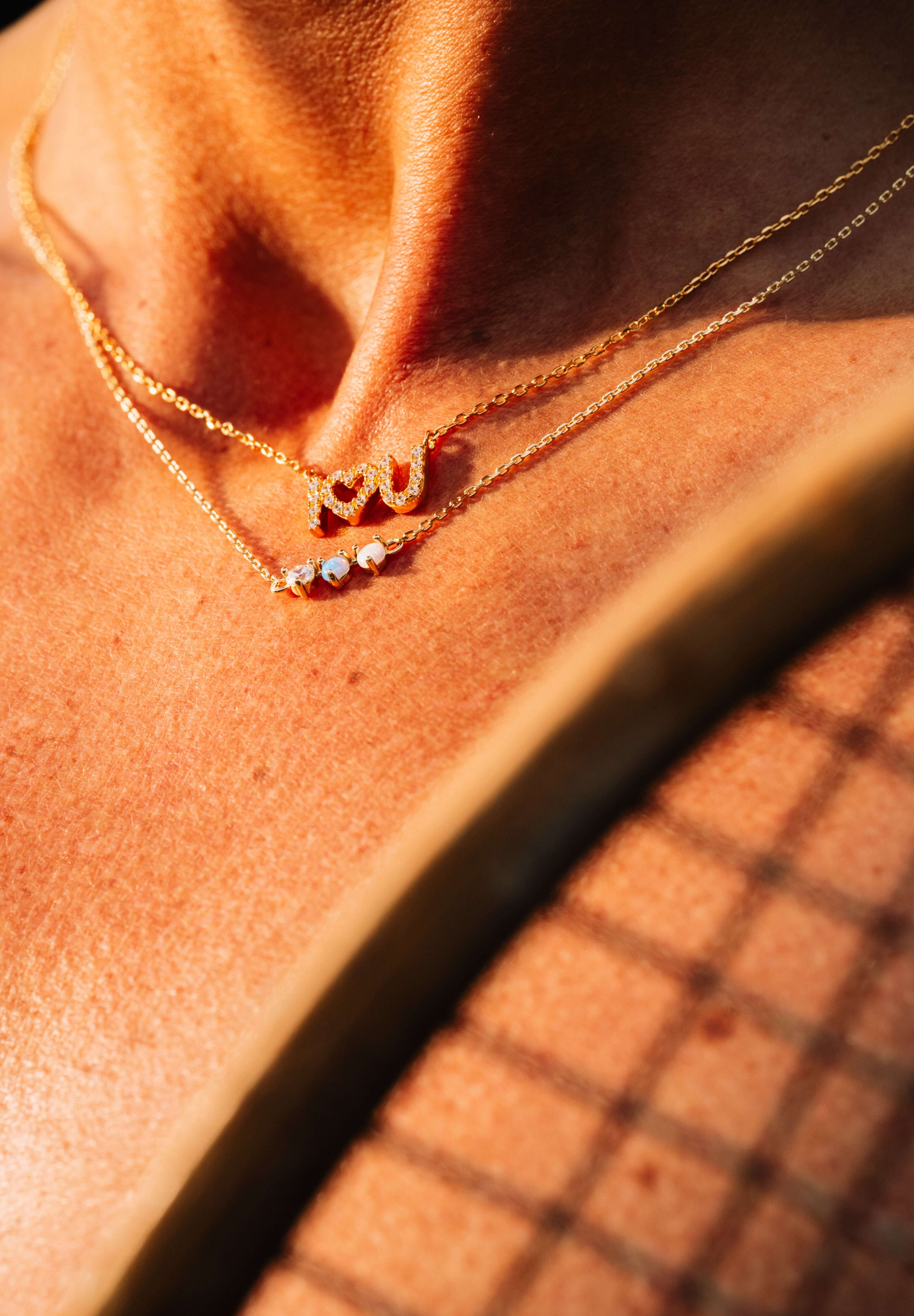 Starburst Opal Pendant Necklace elegantly layered with delicate gold chains, showcasing a minimalist style.
