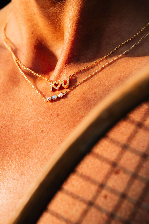 Starburst Opal Pendant Necklace elegantly layered with delicate gold chains, showcasing a minimalist style.