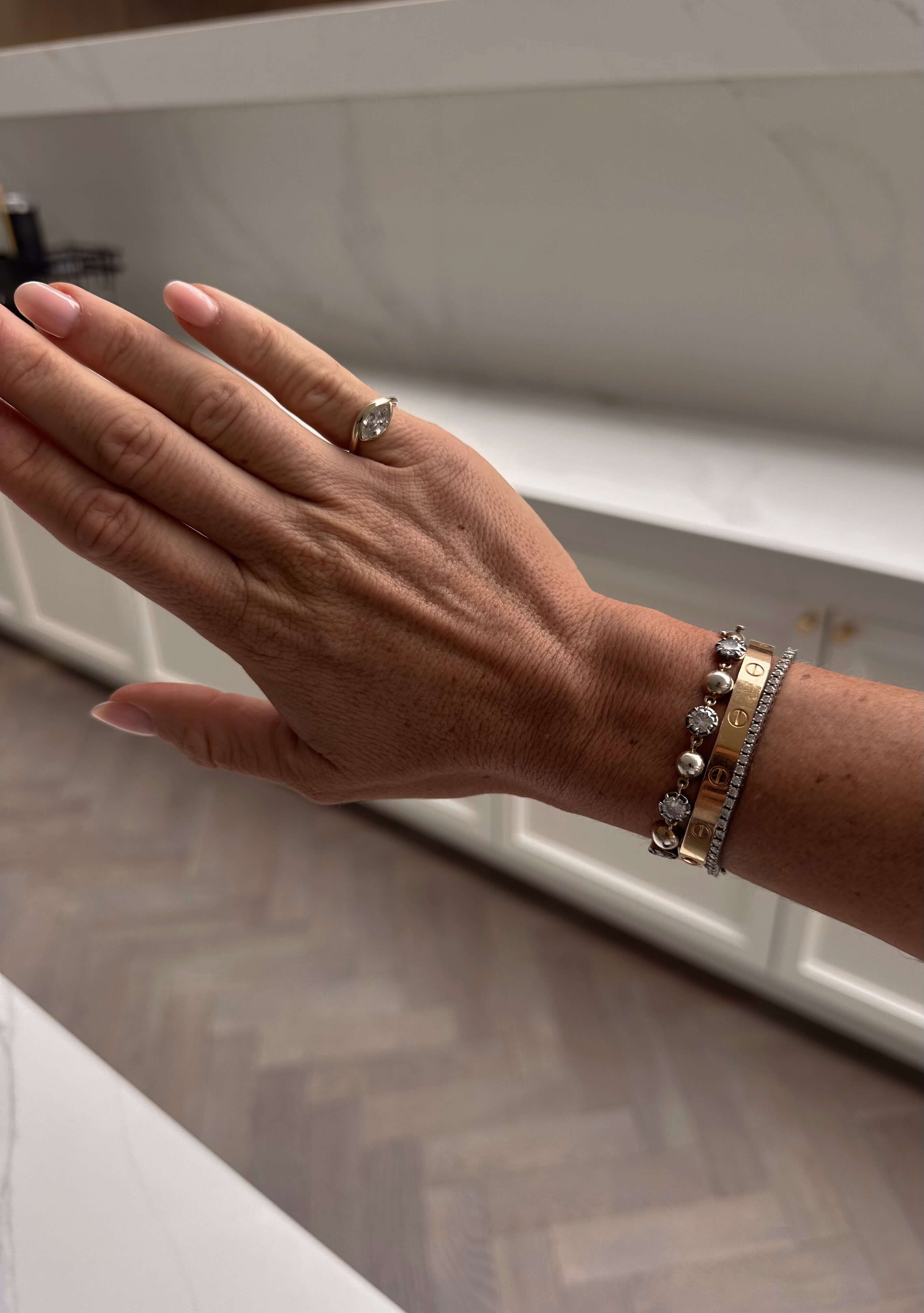 Soft Life Gold East West Pinky Ring worn on hand with stylish bracelets in elegant setting.