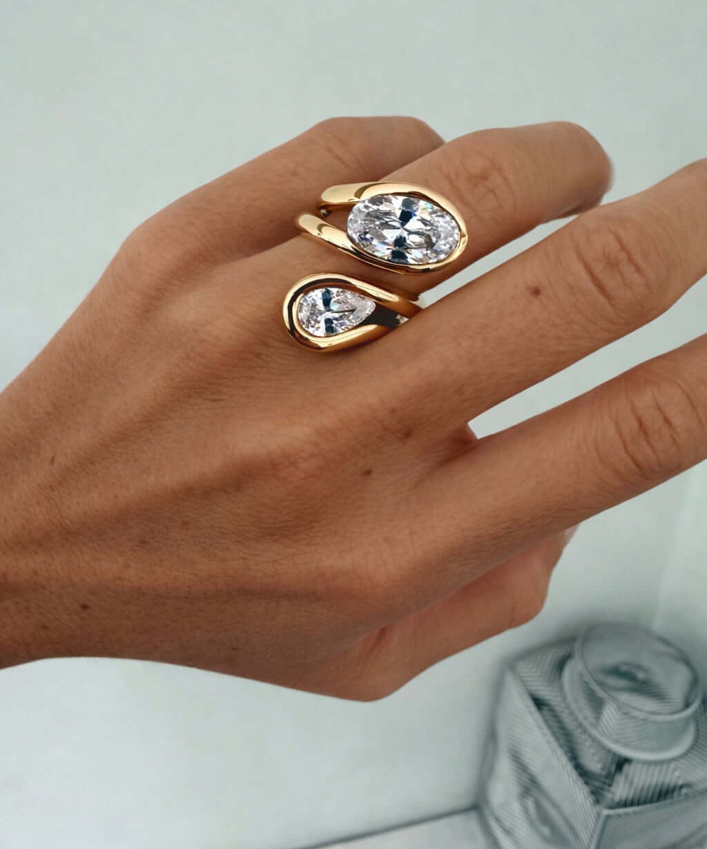 Close-up of a hand wearing the Can’t Compare Ring featuring two light-catching stones in a sculptural design.