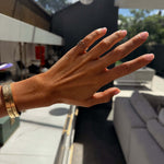 Hand wearing the Dilly Dally Pinky Ring, showcasing its elegant design and wider bracelets in a stylish setting.