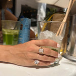 Hand wearing Be Your Own Muse Gold Ring holding a glass of ice and a refreshing drink in a sunny outdoor setting.